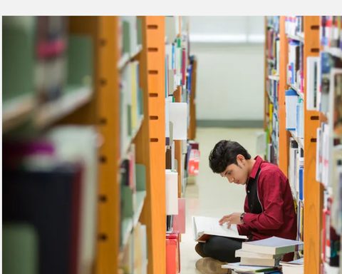 文章封面：少年在書架間席地閱讀